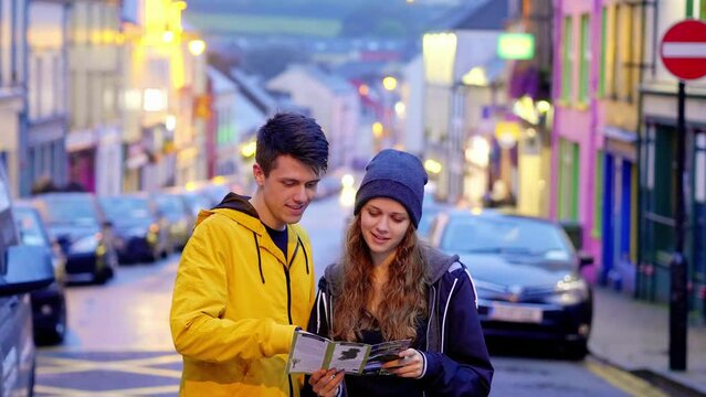 Young couple looking at a map in the town of Dingle in Ireland - slow motion clip 