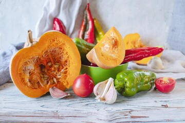 Pumpkin slices and fresh ripe assorted vegetables for cooking dinner on a wooden rustic table