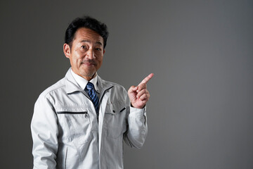 右側を指差すミドルエイジの作業員　黒背景