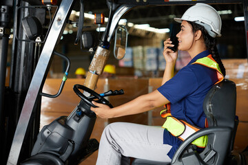 Indian worker driving a forklift and using walkie talkie in warehouse storage