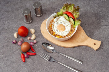 Obiad z kuchni azjatyckiej na drewnianej desce do krojenia w białej misce, rice bowl z ryżem, warzywami, jajkiem i kurczakiem