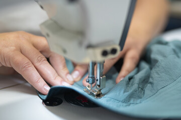 workers in an industrial garment factory sew clothes on sewing machine