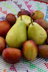 FRESH BRITISH PEARS AND PLUMS ON TRADITIONAL WOVEN EMBROIDERED AFRICAN MAT