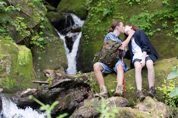 Naklejka premium Young couple hiking in the forest with backpacks and trekking poles