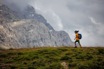 Obraz premium boy with a backpack on a hike against the backdrop of the mountains. child traveler with backpack, hiking, travel, mountains in the background, kids summer vacation.