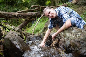 Naklejka na ściany i meble Hiker in the jungle playing with water in a stream in the forest.