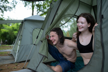 Young couple camping in tent in forest smiling happy and relaxed looking at camera