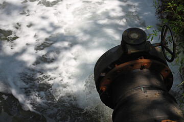 large faucet for dumping waste into the river, steel pipe from the pump to the river in a public...