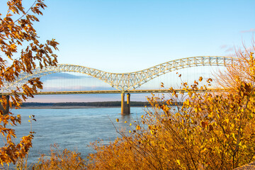 The tied-arch Hernando de Soto Bridge carrying Interstate 40 across the Mississippi River between West Memphis, Arkansas, and Memphis, Tennessee as seen from Mud Island Park on sunset with fall colors