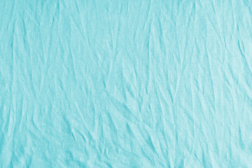 Wrinkled, crumpled cyan fabric texture background. Wrinkled and creased abstract backdrop of cotton jersey textile, wallpaper with copy space, top view.