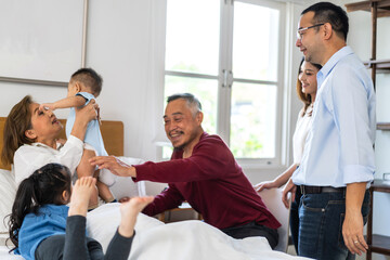 Obraz premium Portrait of happy love asian grandfather with grandmother playing with asian baby and little cute girl on bed.Big family love with their laughing grandparents smiling together.Family and togetherness
