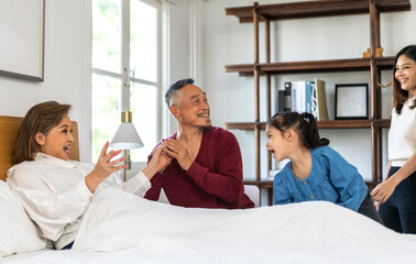 Portrait of happy love asian grandfather with grandmother playing with asian baby and little cute girl on bed.Big family love with their laughing grandparents smiling together.Family and togetherness