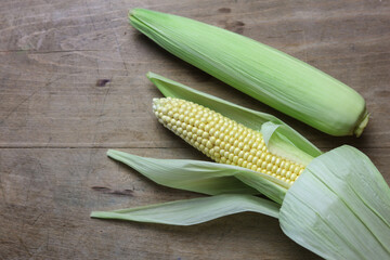a close up of freshly picked sweet corn on a wooden table