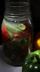 Fermeted pickled peppers in the glass jar with dark background and copy space