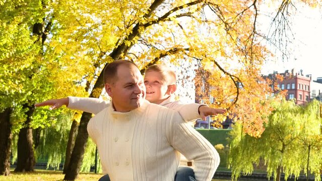 Son and father have fun playing airplanes outdoors on a sunny autumn day. Horizonta video
