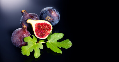 Fig fruits. Ripe sweet fresh figs fruit with leaves close up, on black background with water drops