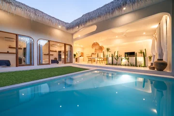 Fototapeten Tropical villa view with garden, swimming pool and open living room at sunset © Roman