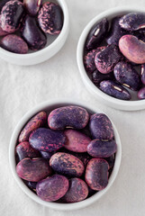 Purple pink scarlet runner beans in white bowls close up.
