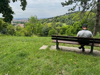 Man sitting on bench on hill in front of Verona city Italy