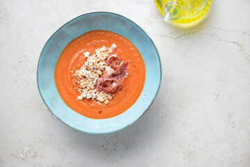 Turquoise bowl with spanish salmorejo cordobes on a light-beige stone background, horizontal shot with space, above view
