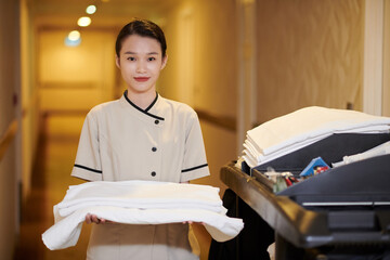 Portrait of smiling hotel maid holding stack of fresh fluffy flowers
