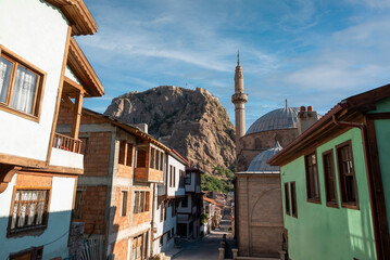 Traditional Turkish Ottoman houses in Afyonkarahisar Turkey. Afyon Castle on the rock and Mevlevihane Museum in front of it