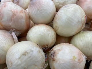 White onions in a pile on display in a grocery store