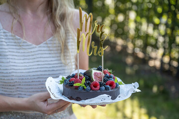 beautiful delicious Wedding cake with fresh wild berries and fruits Mrs Ms Sign on Top