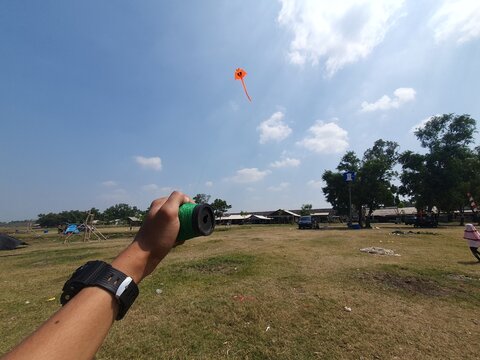 The hand is playing the kite while holding the kite string