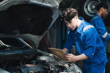 Two auto mechanic working with car diagnostic tool in a repair shop.