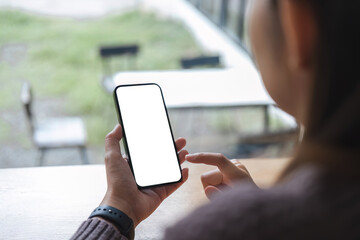 Mockup image of closeup woman hand holding mobile phone with blank white smartphone screen at the outdoor.