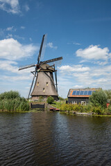 iconic smock ground sailer windmill in Kinderdijk Netherlands. Landmark buildings originally made to pump water out of low land polder to preserve land reclaimed from the sea. Solar sun panels on shed