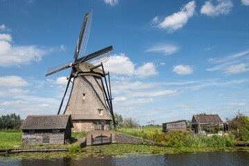 Naklejka premium iconic smock ground sailer windmill in Kinderdijk Netherlands. Landmark buildings originally made to pump water out of low land polder to preserve land reclaimed from the sea