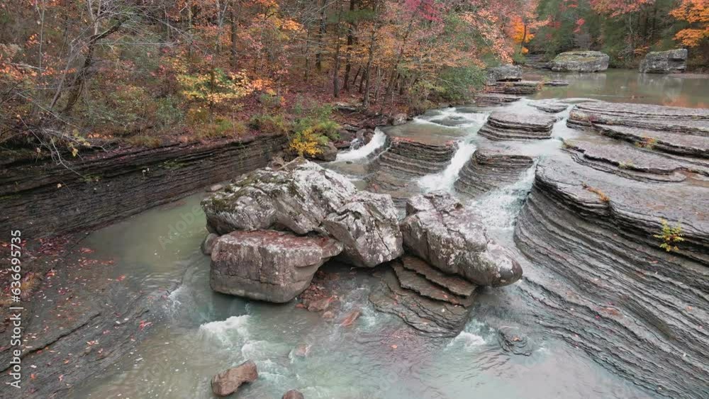 Wall mural multiple waterfalls flow over rock cascade from a stream in the mountains during autumn with fall co
