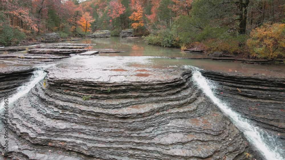 Wall mural multiple waterfalls flow over rock cascade from a creek in the mountains during autumn with fall col
