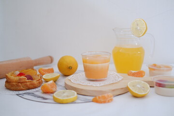 Fresh orange juice in a glass with fresh fruits on a white background