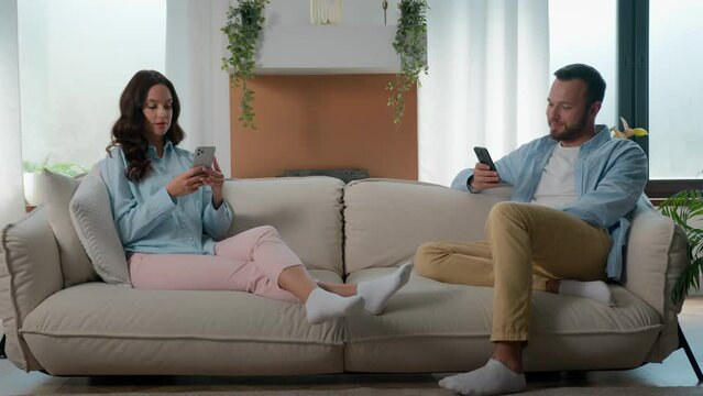 Caucasian gadget addict couple busy with phones scrolling social media smartphone gaming ignoring each other internet addiction overuse mobile app at home couch family man woman cellphones addicted