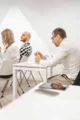 Middle-aged male person playing with his pen during meeting at modern conference room