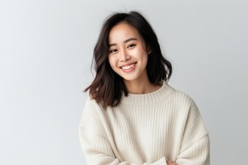 Medium shot portrait of a Chinese woman in her 20s in a white background wearing a cozy sweater - obrazy, fototapety, plakaty