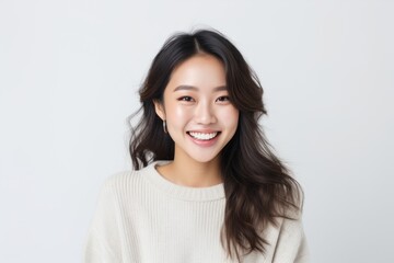 Lifestyle portrait of a Chinese woman in her 20s in a white background wearing a cozy sweater