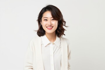 Fototapeta premium Medium shot portrait of a Chinese woman in her 20s in a white background wearing a chic cardigan