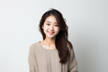 Fototapeta premium Medium shot portrait of a Chinese woman in her 20s in a white background wearing a chic cardigan