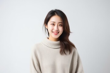 Medium shot portrait of a Chinese woman in her 20s in a white background wearing a cozy sweater