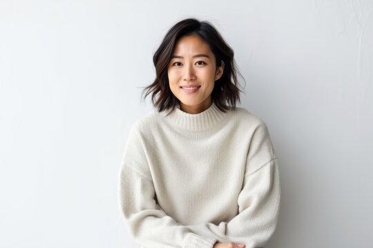 Medium shot portrait of a Chinese woman in her 30s in a white background wearing a cozy sweater
