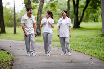 Asian Seniors and Daughter Walking Relax in the Park, Family Bonding in Nature, Seniors and Family Enjoying Exercise and Relaxation in the Green Park, Health Care and Family Bonding Concept