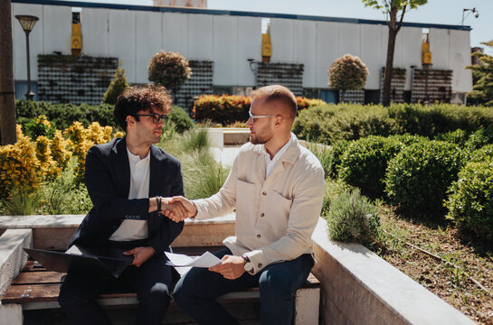 Two businessmen shaking hands after they made successful deal about the project. Front view photo