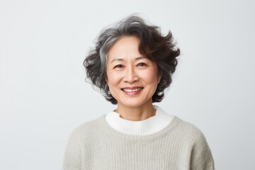 Medium shot portrait of a Chinese woman in her 50s in a white background wearing a cozy sweater