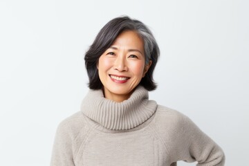 Lifestyle portrait of a Chinese woman in her 50s in a white background wearing a cozy sweater