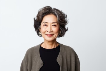 Medium shot portrait of a Chinese woman in her 50s in a white background wearing a chic cardigan