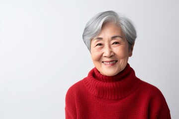 Medium shot portrait of a Chinese woman in her 90s in a white background wearing a cozy sweater